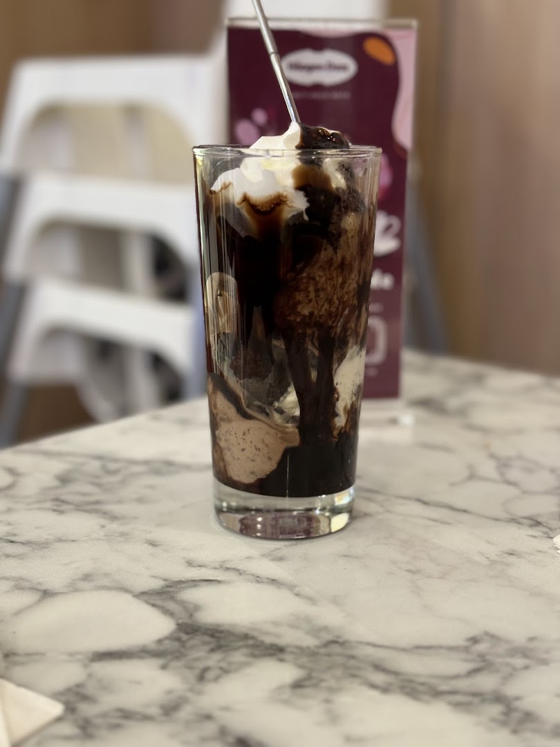 A delicious Häagen-Dazs ice cream sundae with chocolate sauce and whipped cream on a marble table.