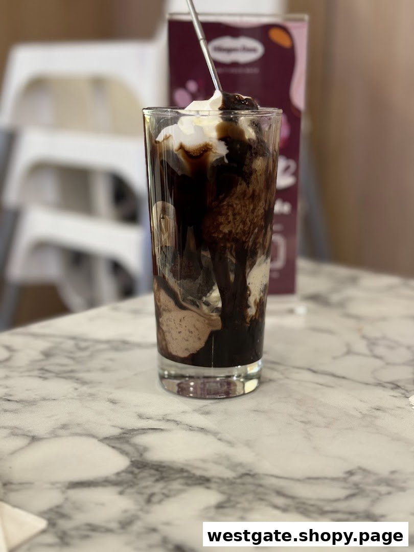 A delicious Häagen-Dazs ice cream sundae with chocolate sauce and whipped cream on a marble table.