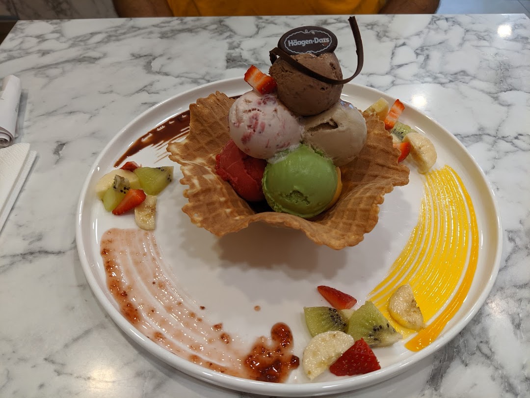 A delightful Häagen-Dazs ice cream dessert with multiple scoops, waffle, and fresh fruit on a white plate.