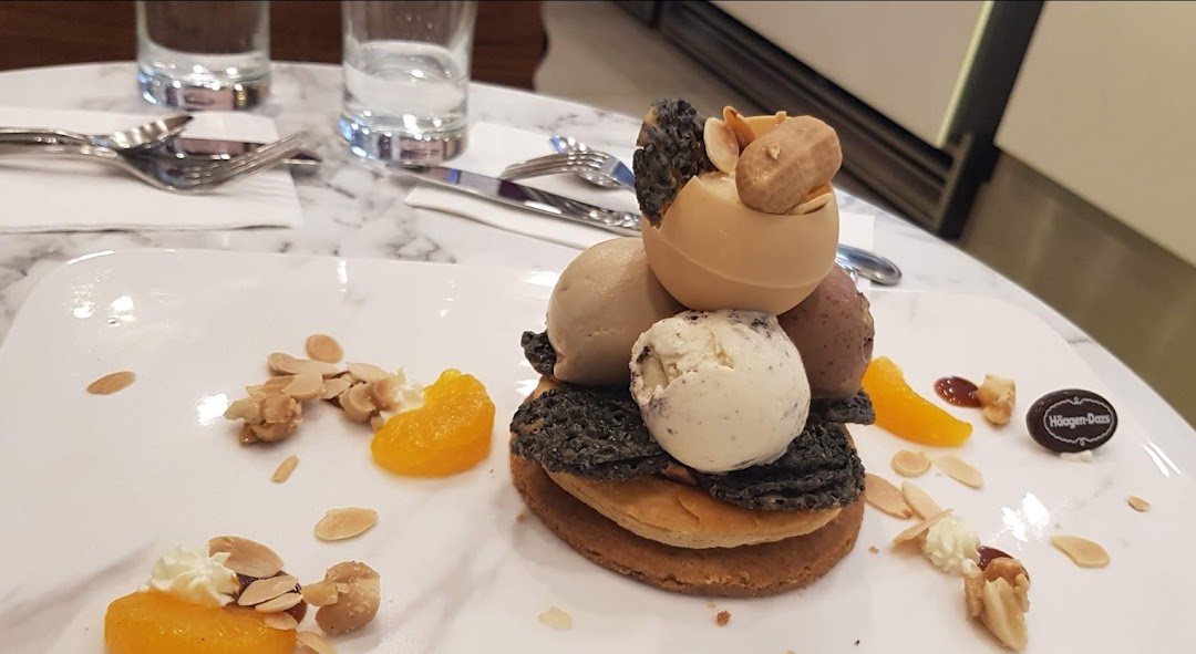 A beautifully plated Häagen-Dazs ice cream dessert with various toppings on a marble table.