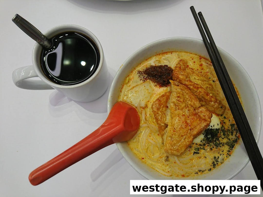 A vibrant bowl of Hainanese curry noodles or laksa served with a cup of traditional coffee.