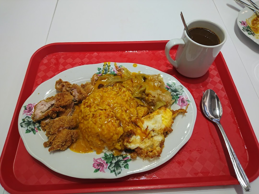 A hearty plate of Hainanese curry rice with crispy fried chicken, fried egg, and cabbage, served with a hot drink.