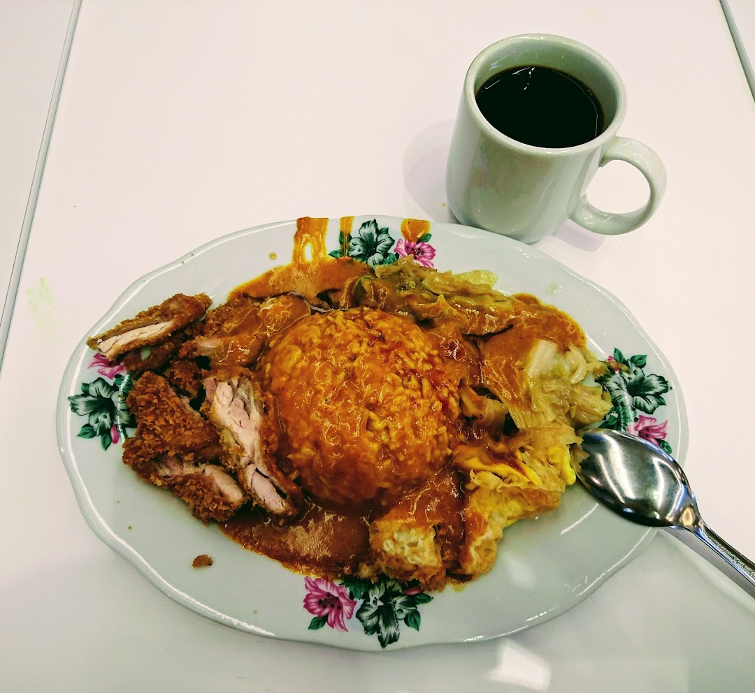 A delicious plate of Hainanese curry rice with crispy fried chicken and a side of coffee.