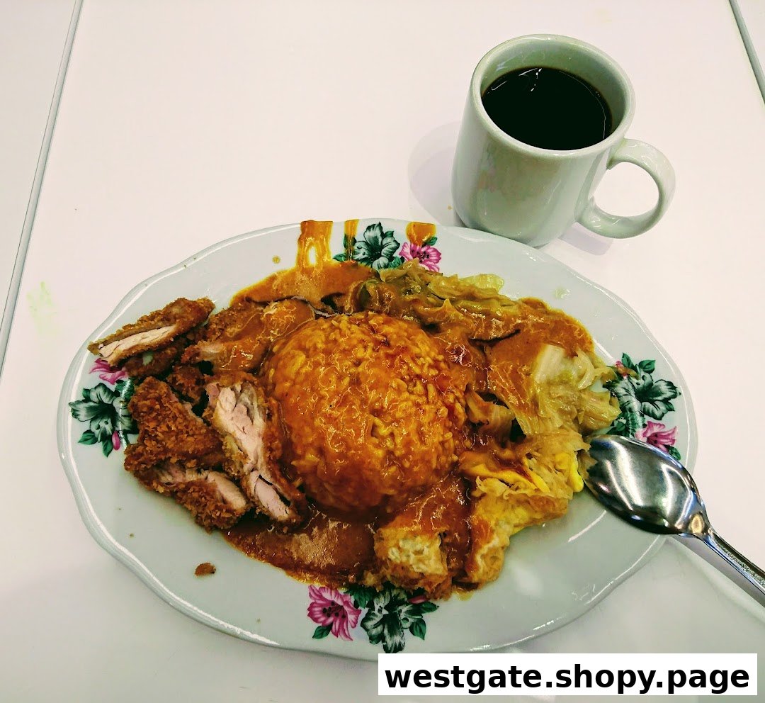A delicious plate of Hainanese curry rice with crispy fried chicken and a side of coffee.
