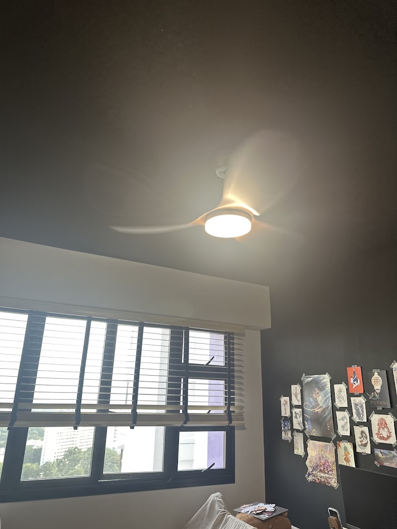 A modern ceiling fan illuminates a room with a large window and a wall adorned with various artworks.