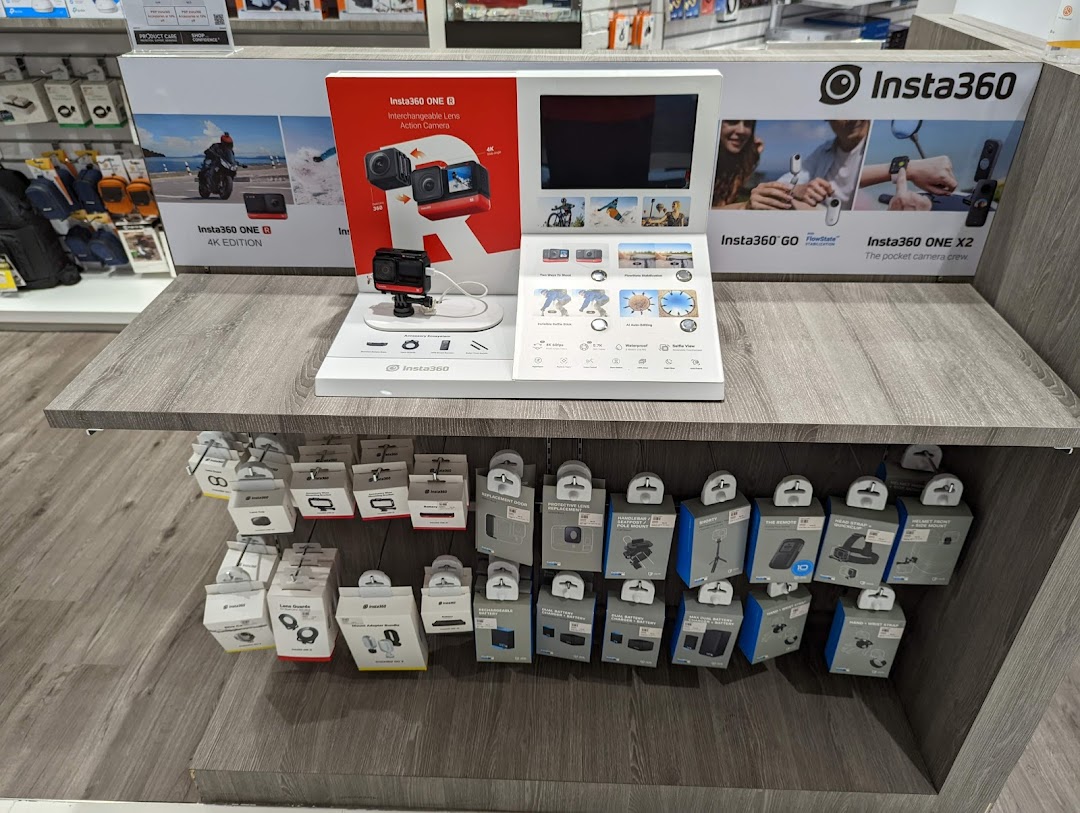 Insta360 camera display with demo unit and various accessories on a retail shelf.