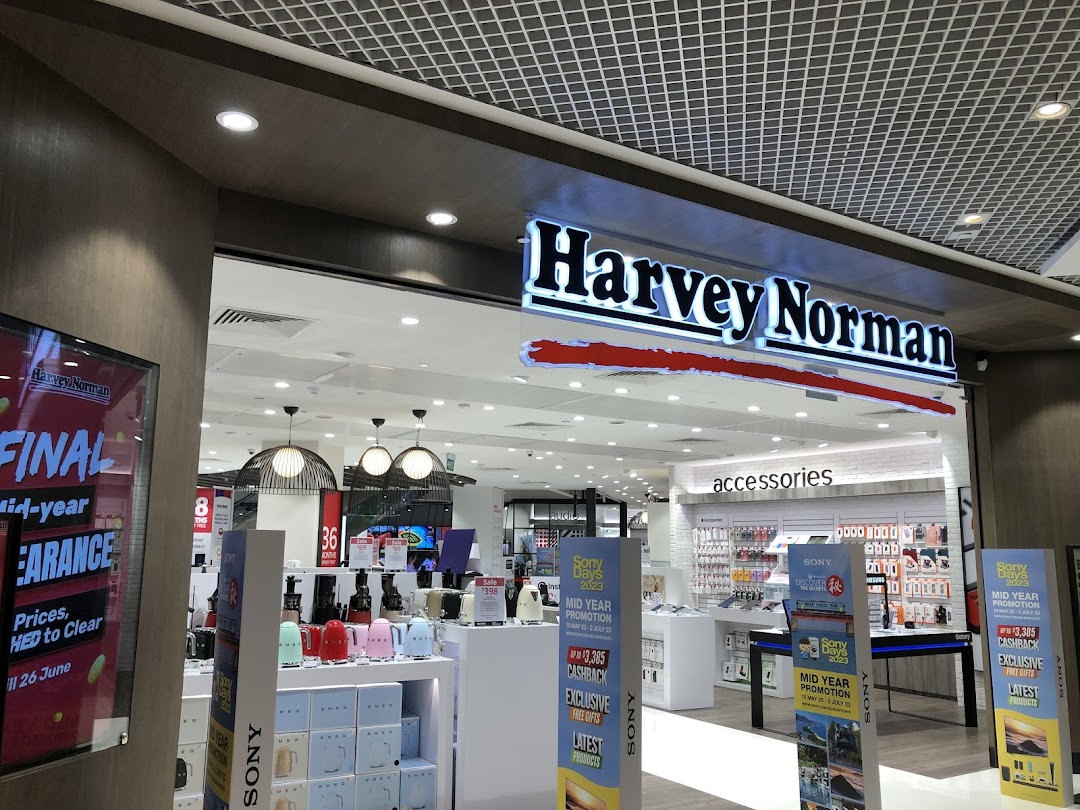 The brightly lit entrance of Harvey Norman, showcasing electronics, home appliances, and accessories with promotional displays.