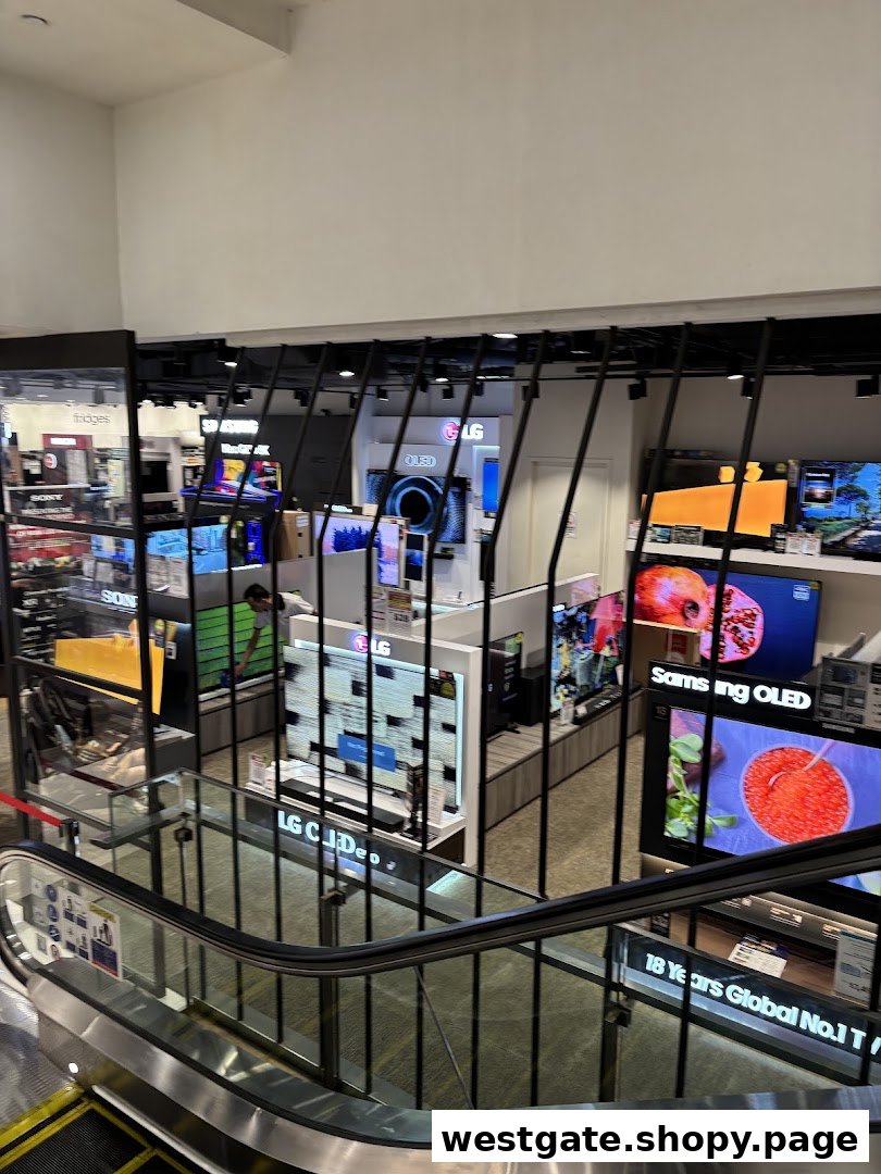 An interior view of Harvey Norman's electronics section, showcasing numerous LG and Samsung OLED televisions from an escalator.
