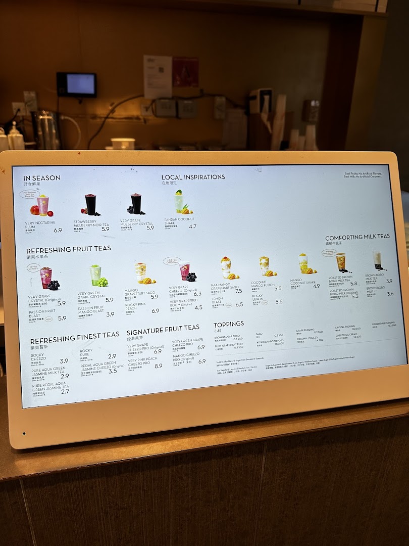 A digital menu board displaying a wide variety of fruit teas, milk teas, and toppings from HEYTEA.
