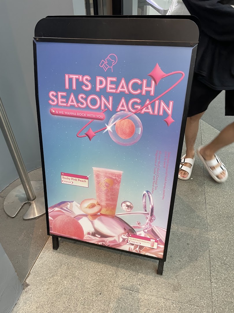 A promotional A-frame sign showcasing HEYTEA's seasonal peach beverages.