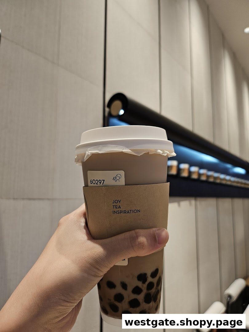 A hand holds a HEYTEA bubble tea with tapioca pearls, featuring a 'JOY TEA INSPIRATION' sleeve.