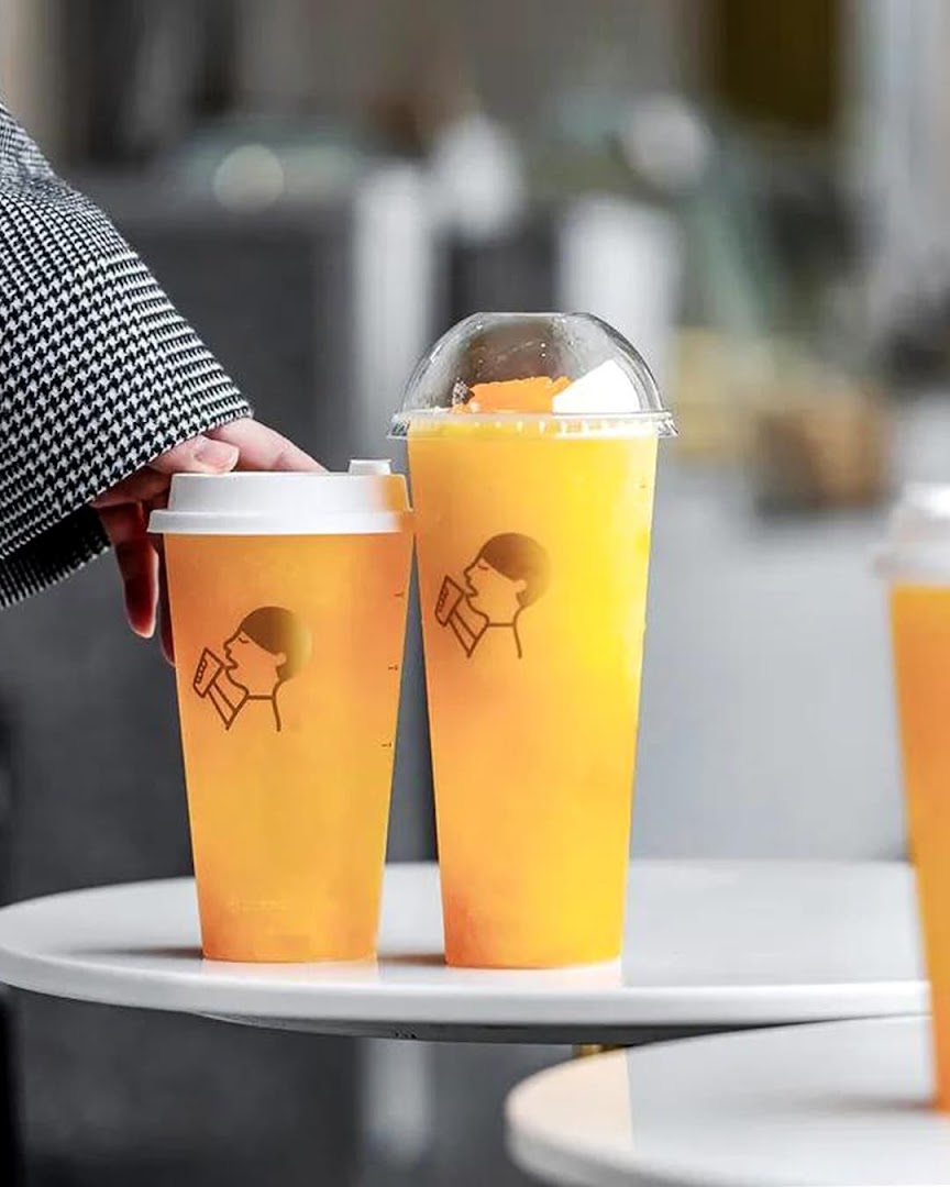 Two refreshing HEYTEA drinks, one with a dome lid, on a white table.