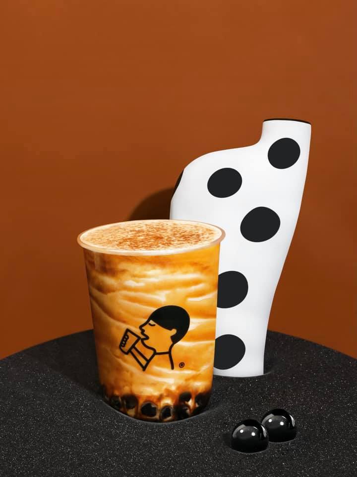A close-up of a HEYTEA bubble tea drink with tapioca pearls and a distinctive logo.