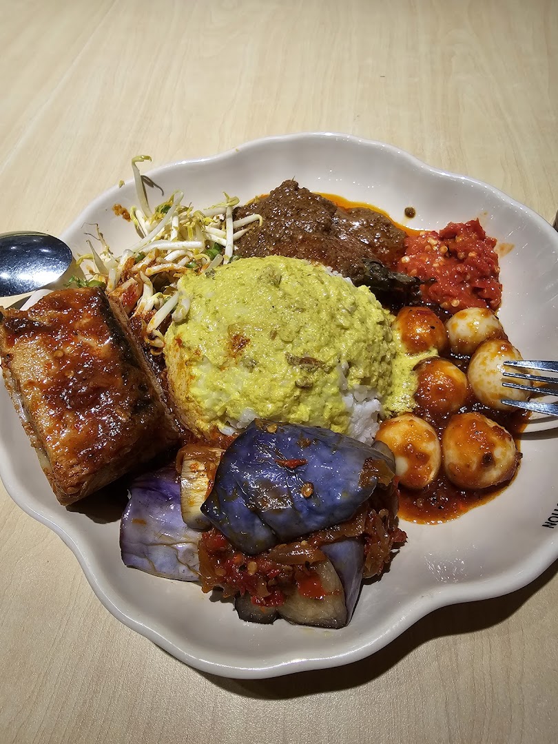 A vibrant plate of traditional Malay/Indonesian cuisine featuring rice, various curries, vegetables, and sambal.