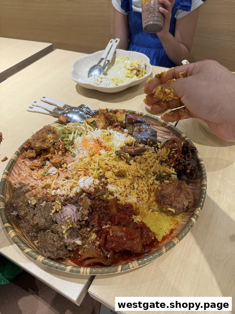 A large, vibrant platter of traditional Malay dishes, likely Nasi Ambeng, being enjoyed by diners.
