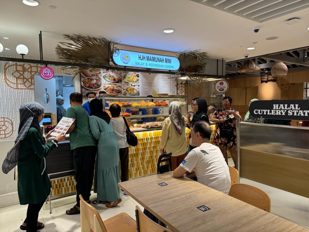 Customers queueing at Hjh Maimunah Mini, a Malay & Indonesian cuisine stall, with various dishes displayed.