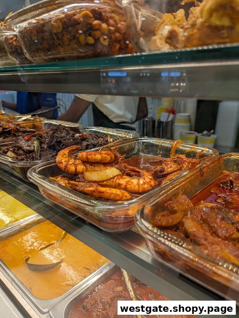 A vibrant display of traditional Malay dishes, including prawns and curries, in a food counter.
