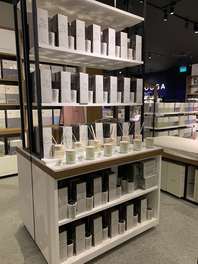 A retail display shelf showcasing a variety of HOOGA home fragrance products, including diffusers and candles.