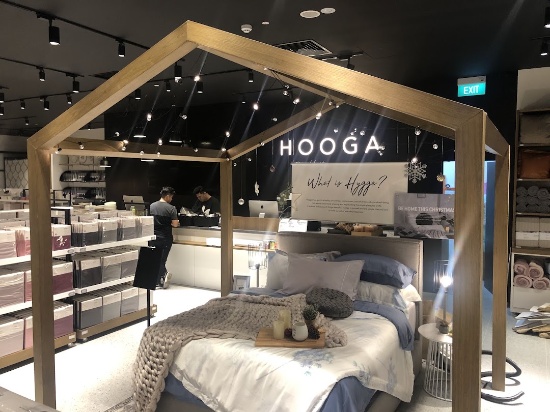 Interior view of HOOGA, showcasing a cozy bed display, cashier counter, and home decor items.