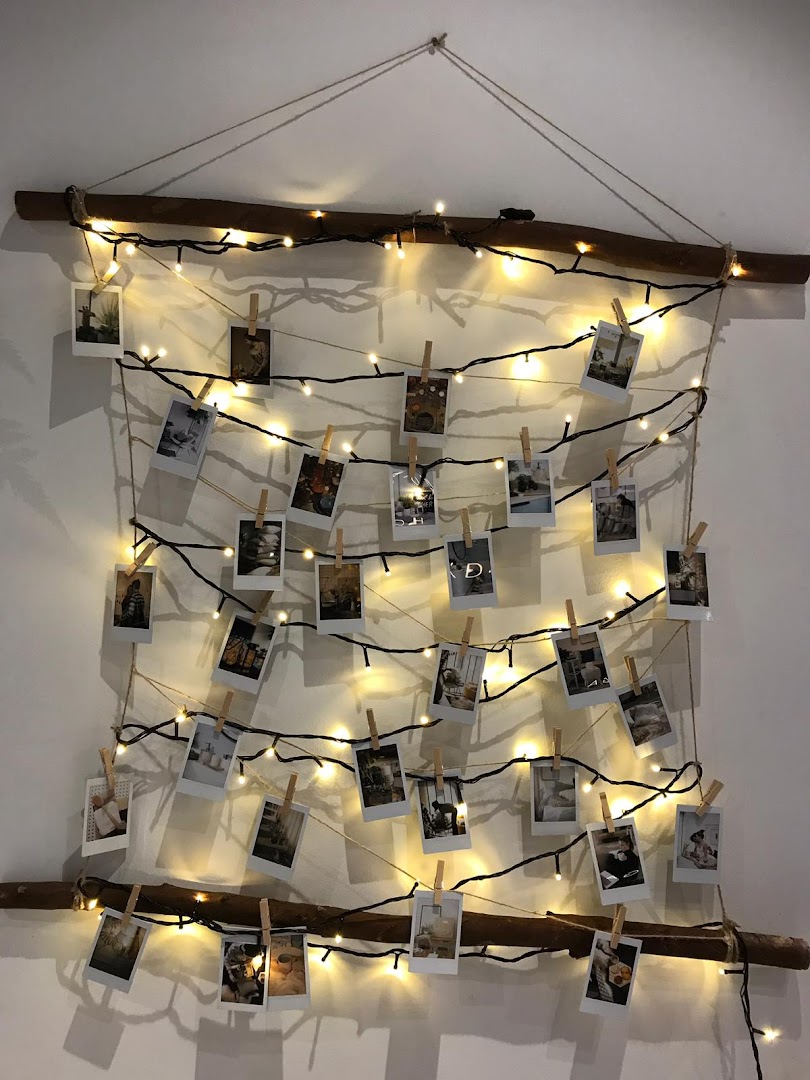 A decorative display featuring string lights, small photos clipped to twine, and natural wooden branches.