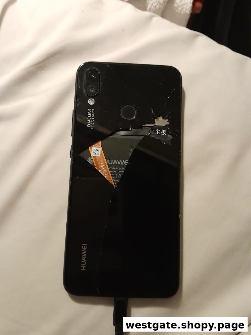A black Huawei smartphone with a severely cracked back panel, revealing internal components.