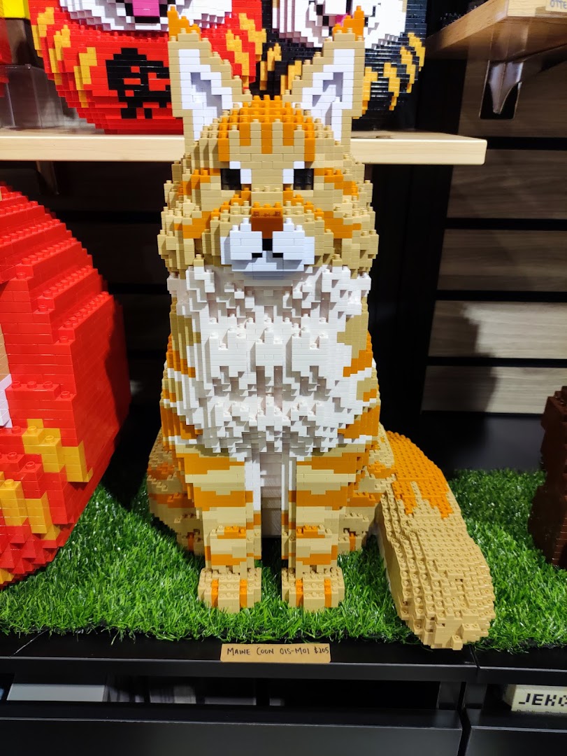 A detailed Maine Coon cat sculpture made from building blocks, displayed on artificial grass.