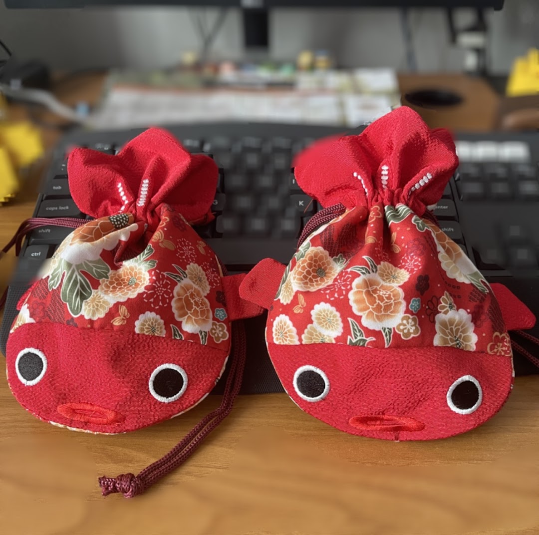 Two charming red fish-shaped pouches with floral patterns, likely decorative items or gifts.