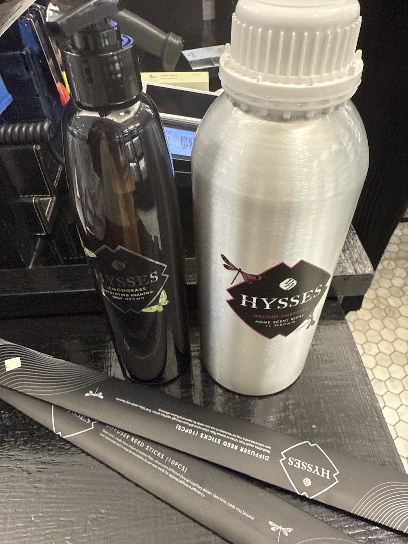 Close-up of HYSSES home scent refill, shampoo, and diffuser reed sticks on a shop counter.