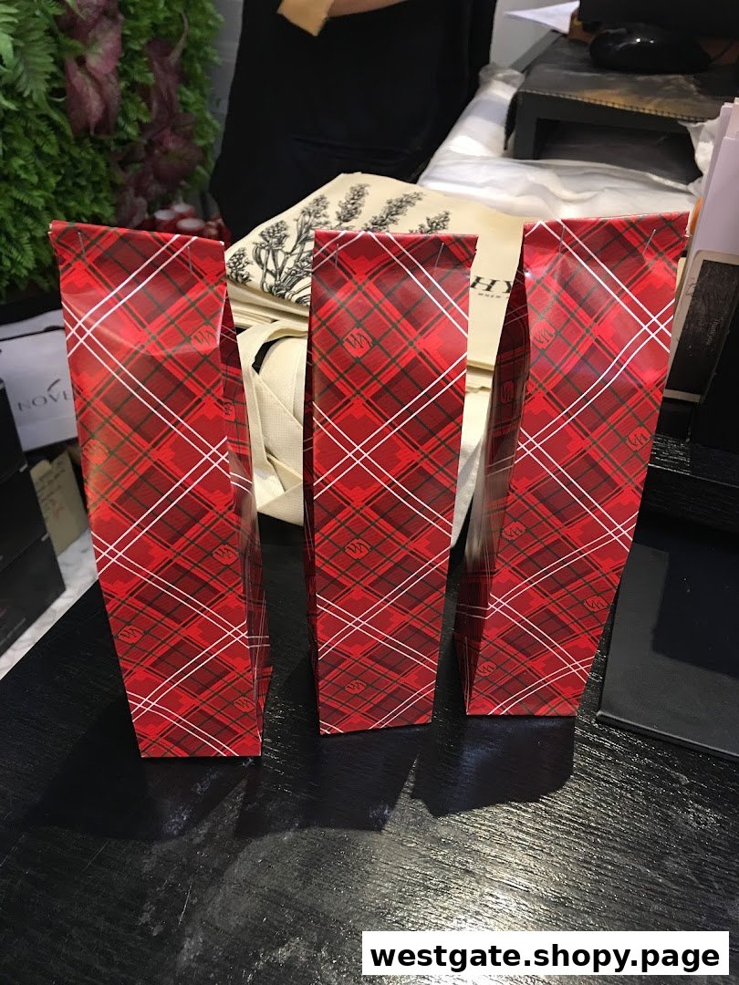 Three festive red plaid gift bags from HYSSES on a dark counter.