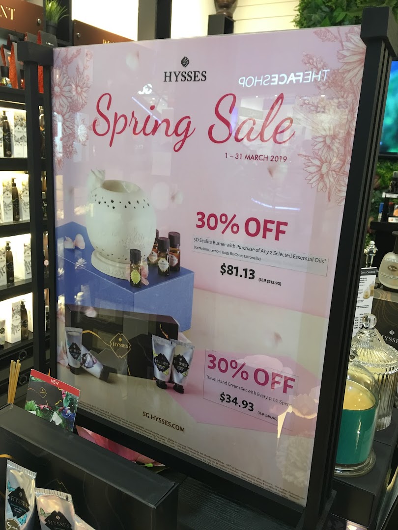A promotional display board for HYSSES' Spring Sale featuring essential oils and hand cream offers.
