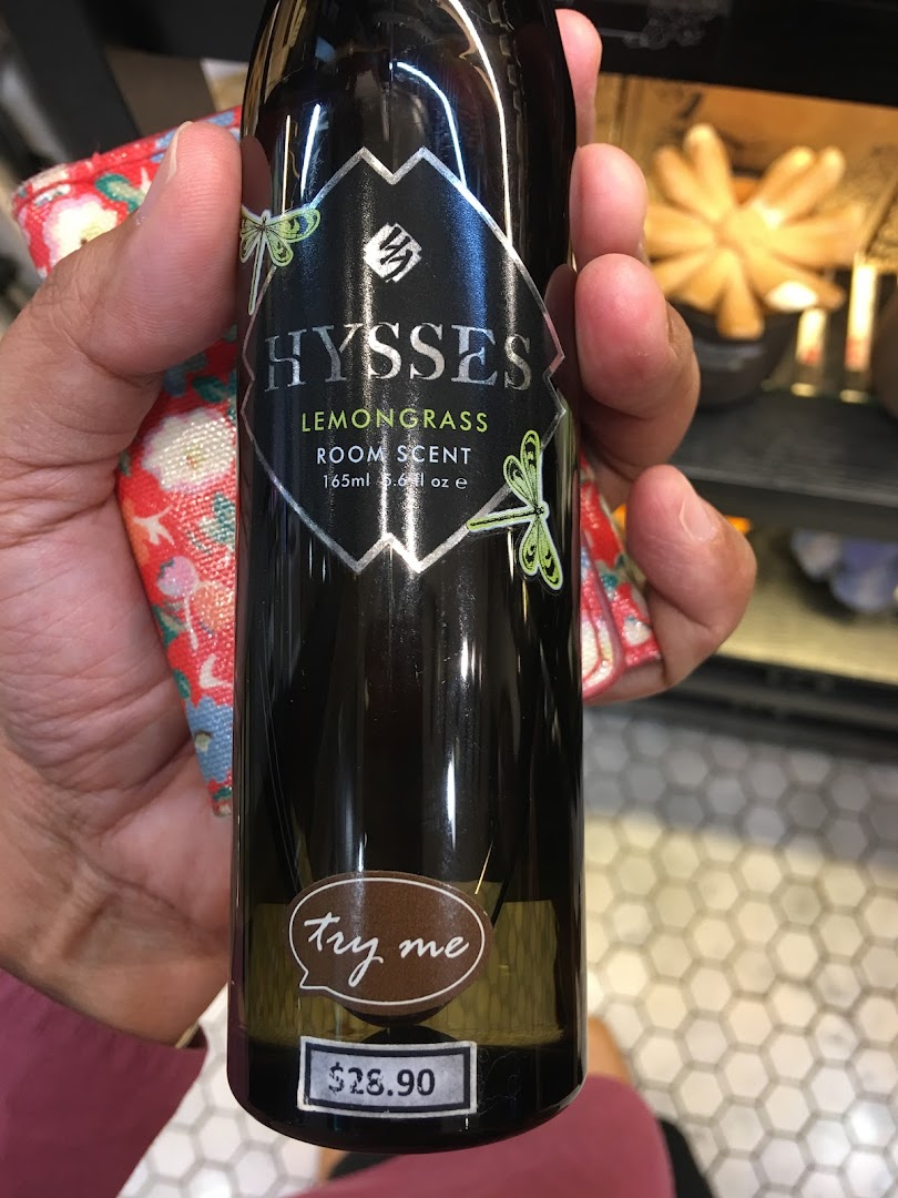 A hand holds a black bottle of HYSSES Lemongrass Room Scent with a price tag.