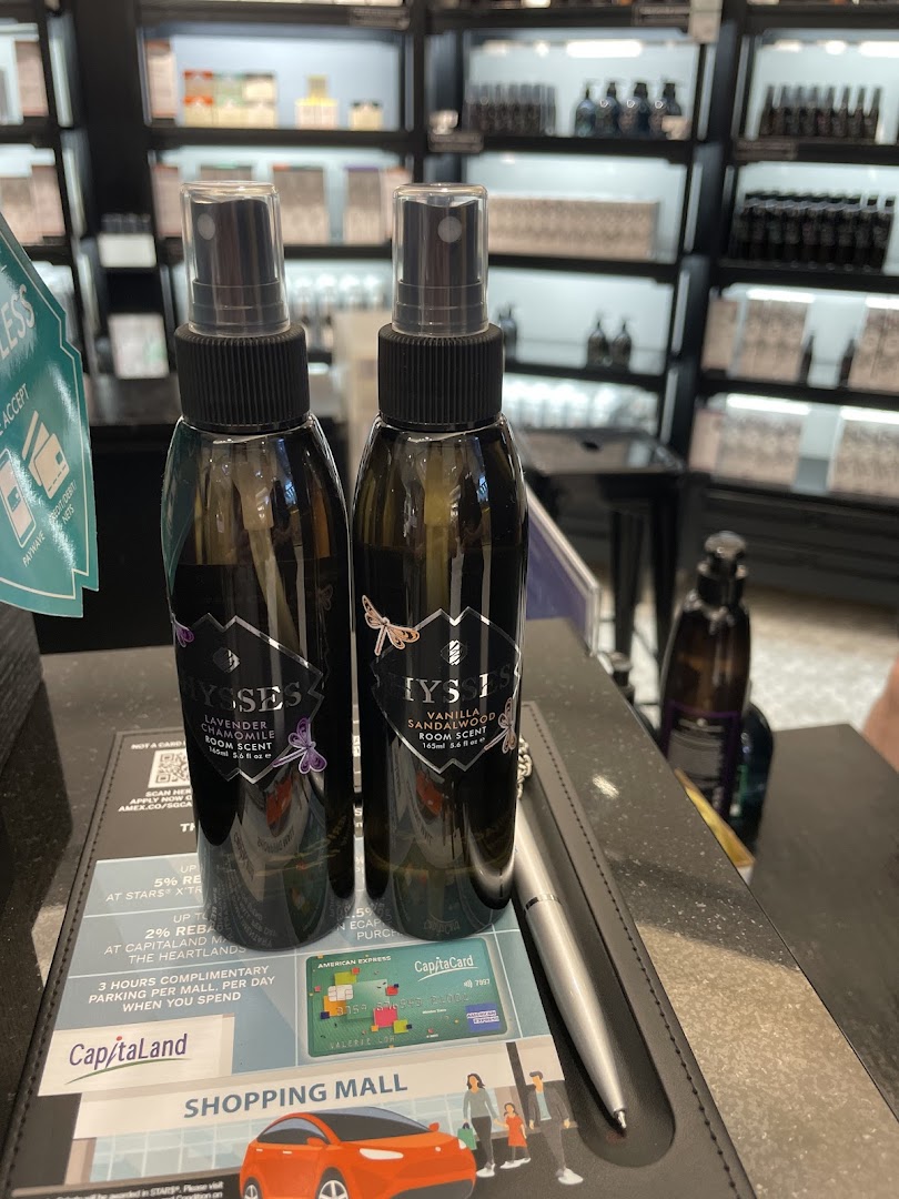 Two HYSSES room scent bottles on a counter, with shop interior and product shelves in the background.