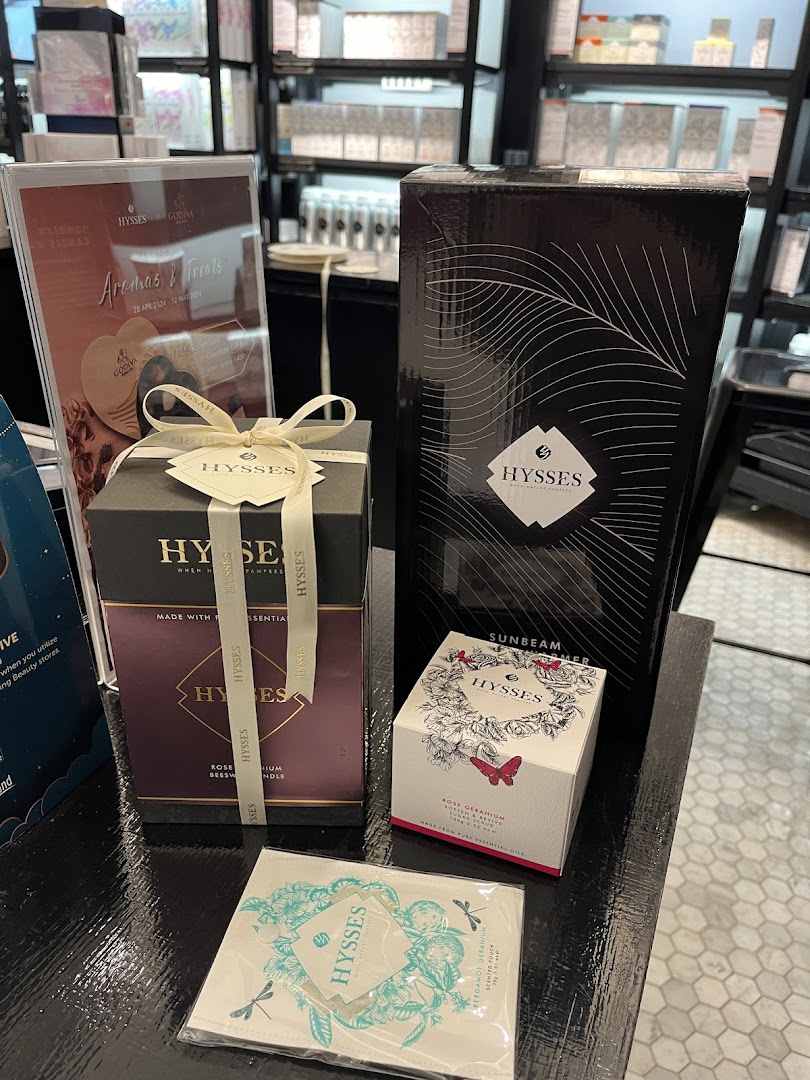 A display of HYSSES home scent products, including candles and diffusers, with a promotional sign.