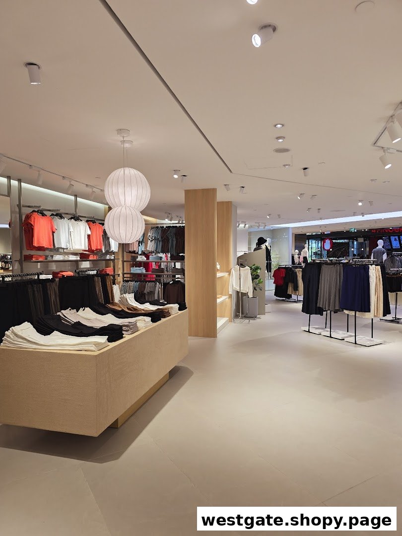 An interior view of a modern clothing store featuring neatly arranged apparel on racks and display tables.