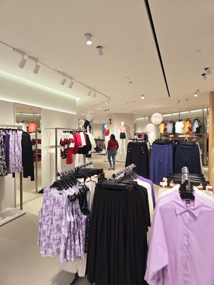 Interior view of a brightly lit clothing store with racks of women's apparel and mannequins.
