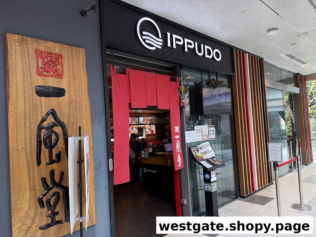 The image shows the inviting entrance of IPPUDO WESTGATE, featuring its prominent logo and traditional red noren curtains.