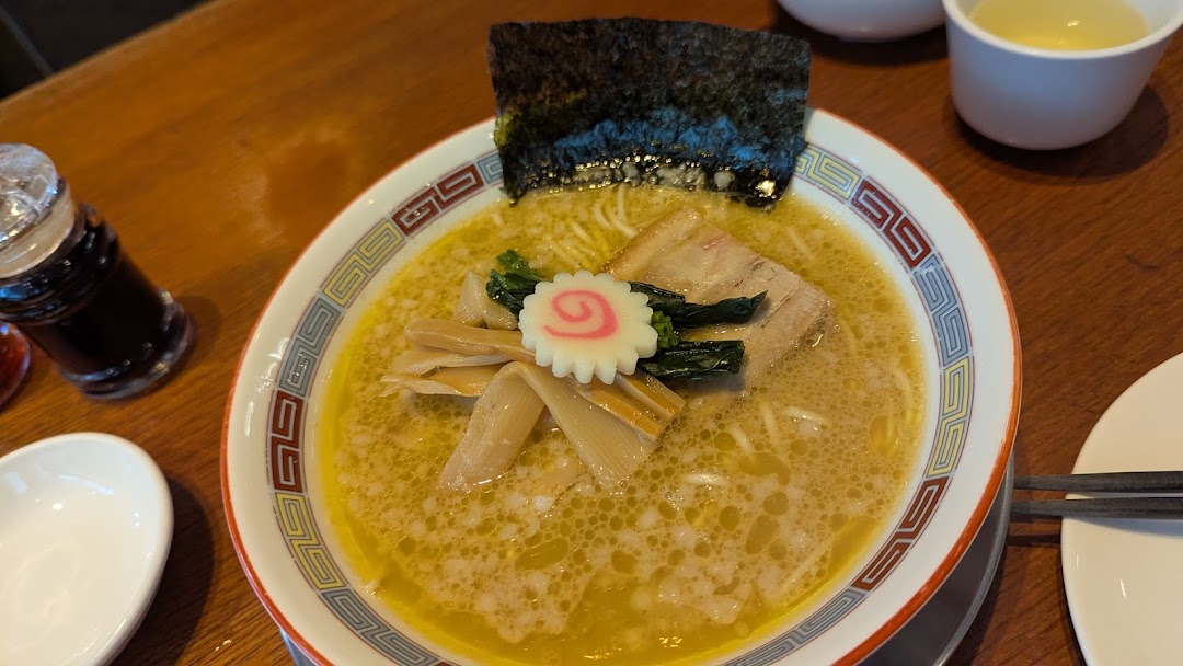 A close-up of a delicious bowl of ramen with pork, seaweed, and fish cake.
