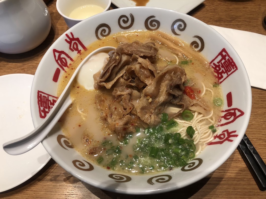 A close-up of a delicious bowl of ramen with tender meat, a soft-boiled egg, and green onions.