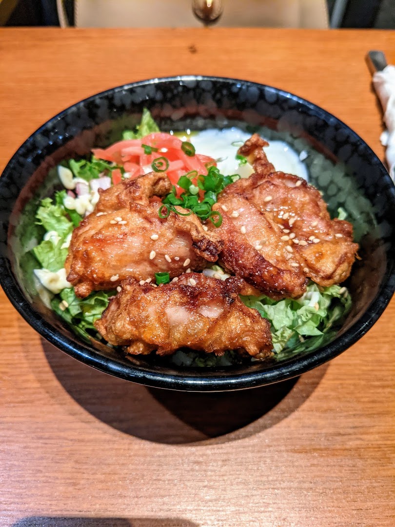 A close-up of crispy fried chicken (karaage) served in a bowl with fresh lettuce and pickled ginger.