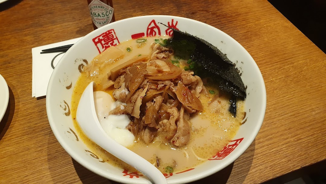 A close-up of a delicious bowl of ramen with pork, egg, and seaweed on a wooden table.
