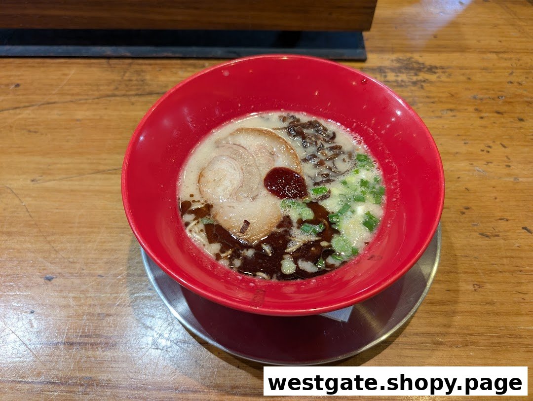A vibrant red bowl of ramen with pork, scallions, and a rich broth on a wooden table.