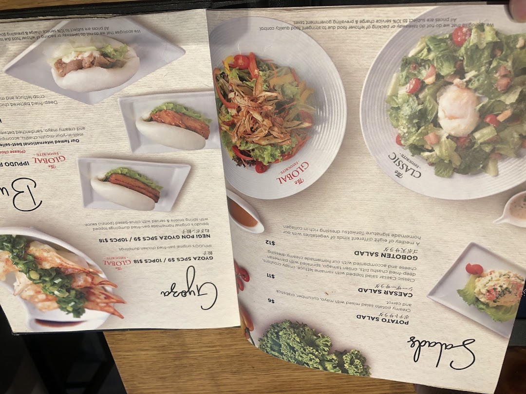 A detailed view of IPPUDO's menu featuring salads, gyoza, and partially visible bun options.
