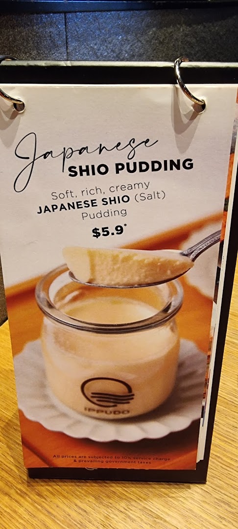 A menu display featuring a Japanese Shio Pudding with a spoon, showing its price and description.