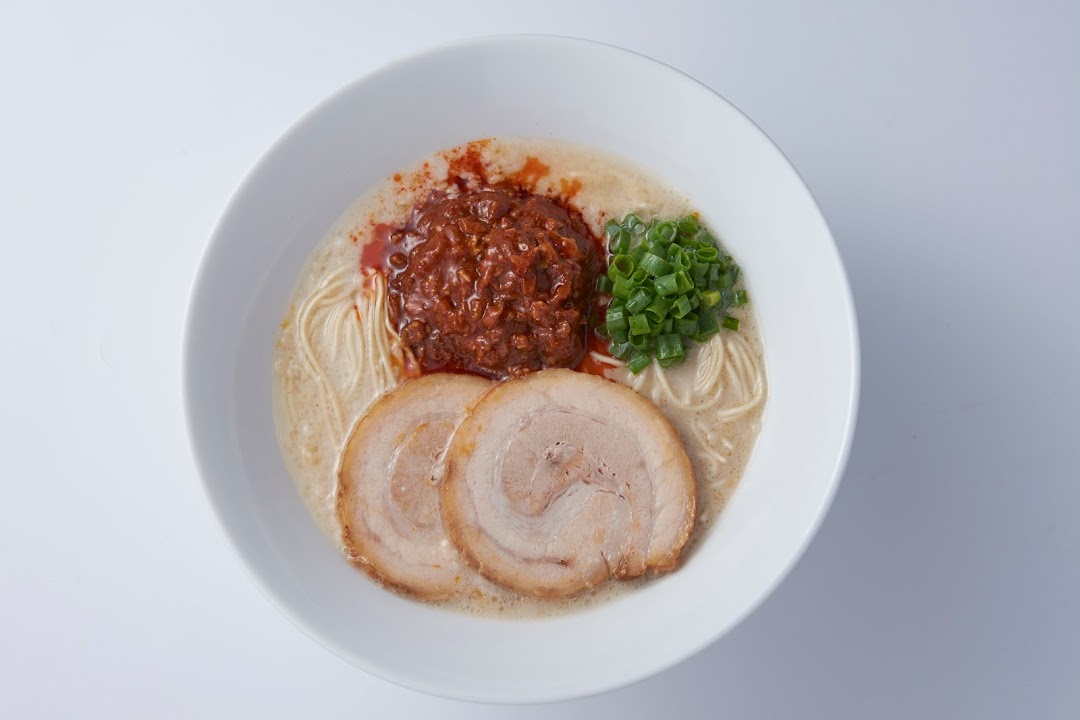 A close-up overhead shot of a delicious bowl of ramen with pork, spicy ground meat, and green onions.