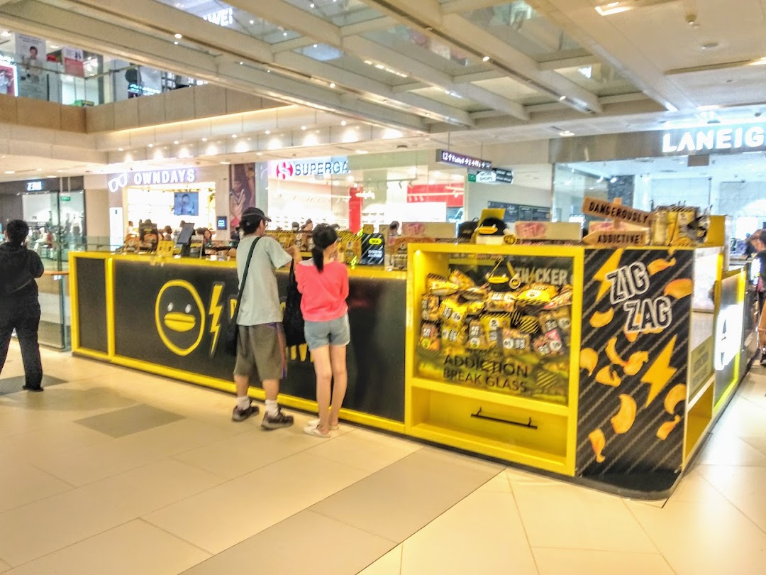 A vibrant black and yellow IRVINS kiosk displaying its signature salted egg snacks in a bustling mall.