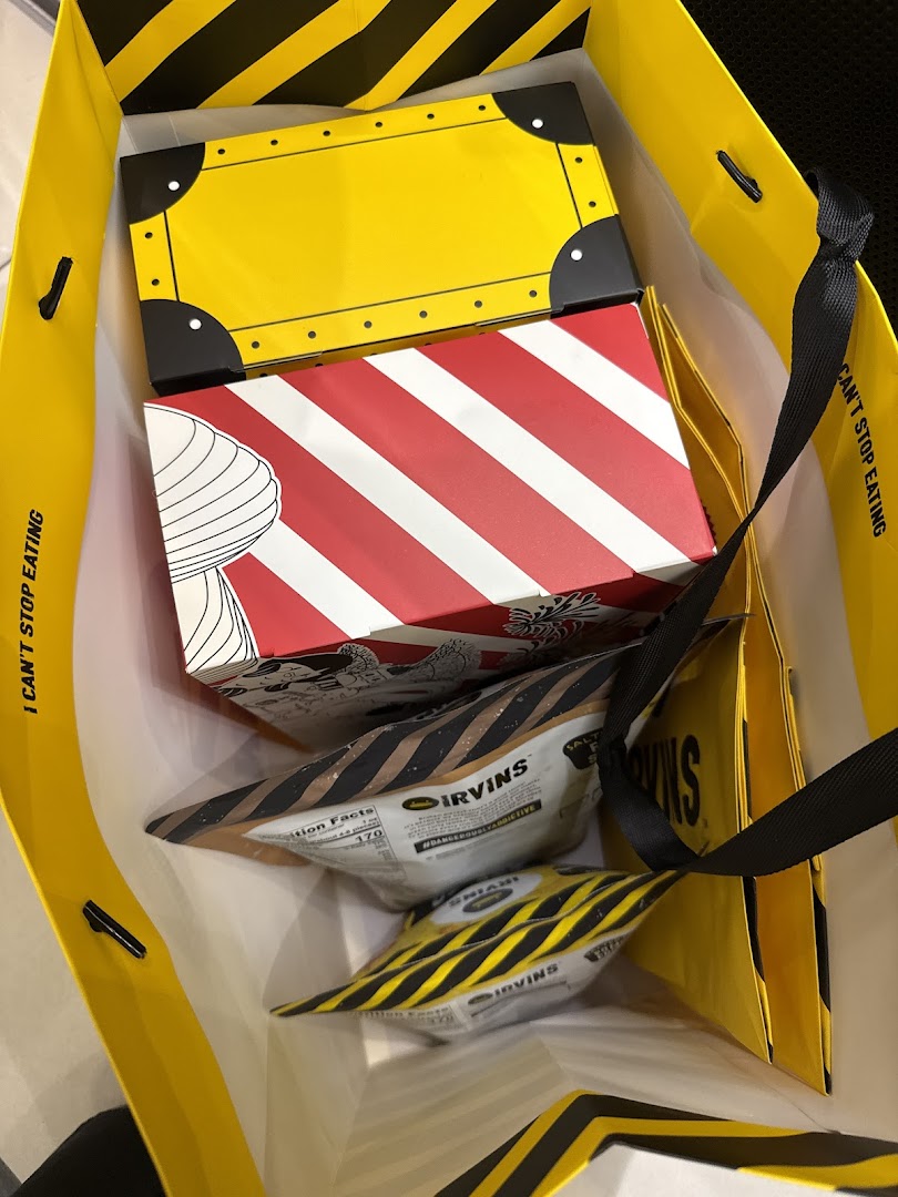 A shopping bag filled with IRVINS' signature salted egg yolk snacks and distinctive packaging.