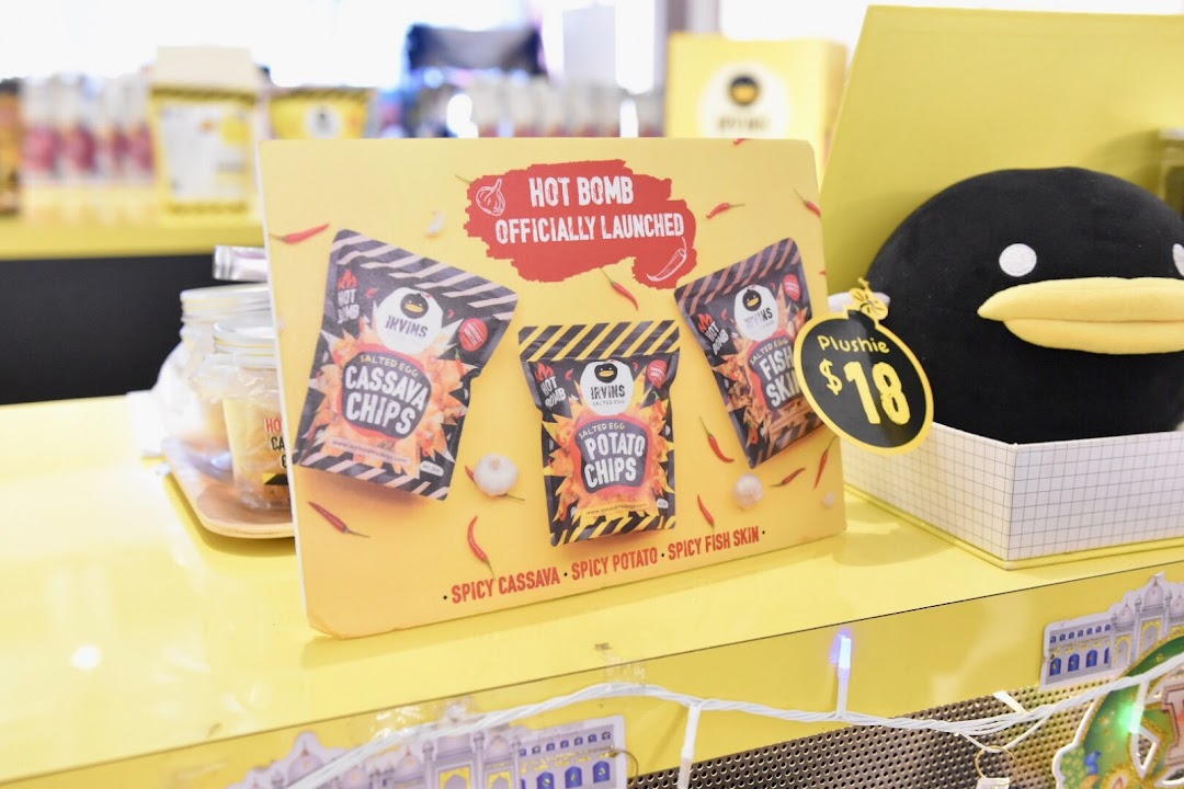 A vibrant display showcasing Irvins' new 'Hot Bomb' spicy salted egg snacks and a cute plushie.