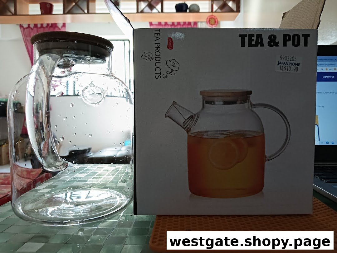 A clear glass pitcher stands next to its 'Tea & Pot' product packaging from Japan Home.