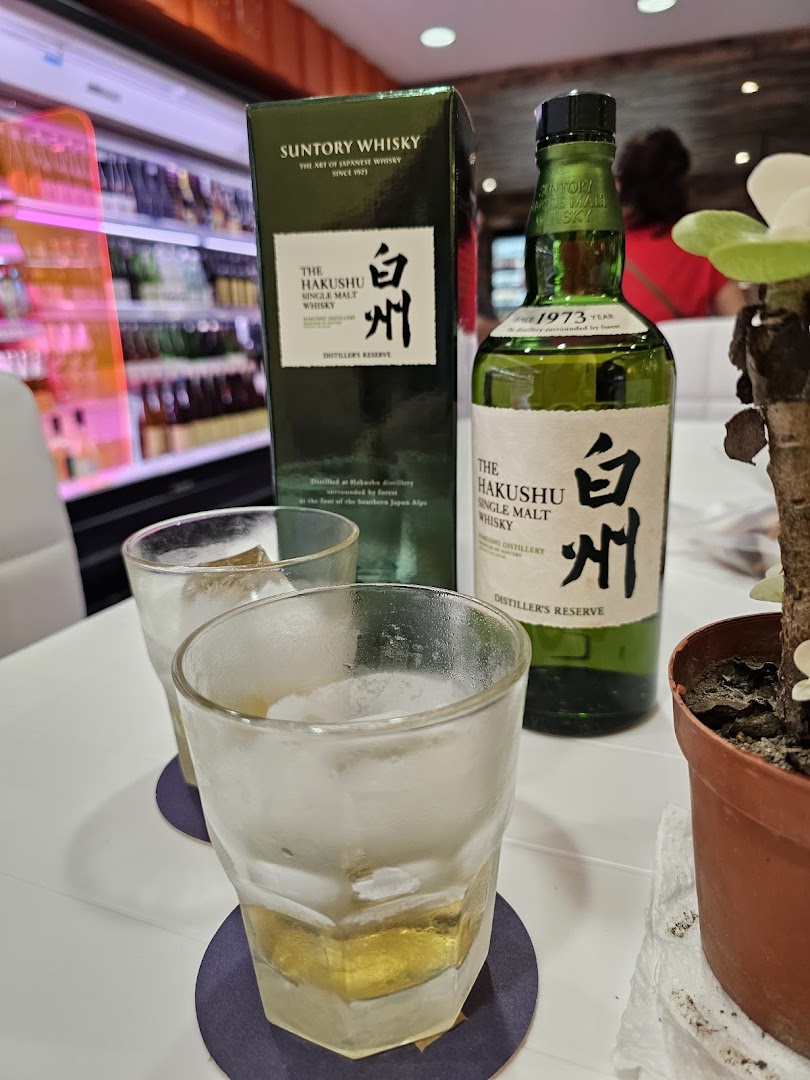Two glasses of whisky with ice and a bottle of Suntory Hakushu on a table at Jays Bar.