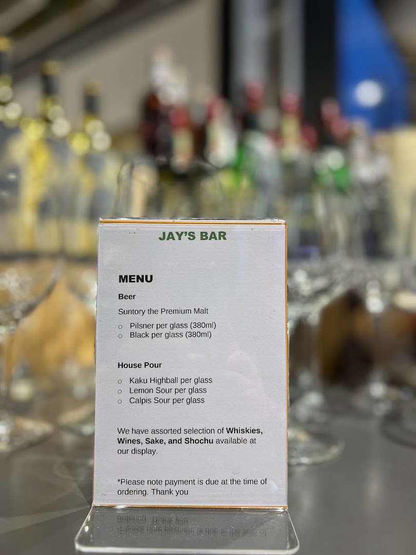 A close-up of Jay's Bar menu, featuring beer and house pour selections, with a blurred bar background.
